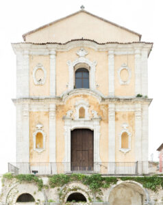 Facciata barocca di edificio storico con porta centrale in legno, finestra e archi in pietra.