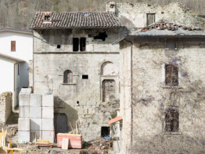 Due edifici antichi in pietra con tetti di tegole, uno con degrado e lavori in corso.