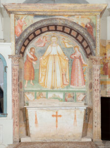 Affresco in nicchia ad arco con figura femminile coronata, angeli e figure laterali, altare in pietra decorato.